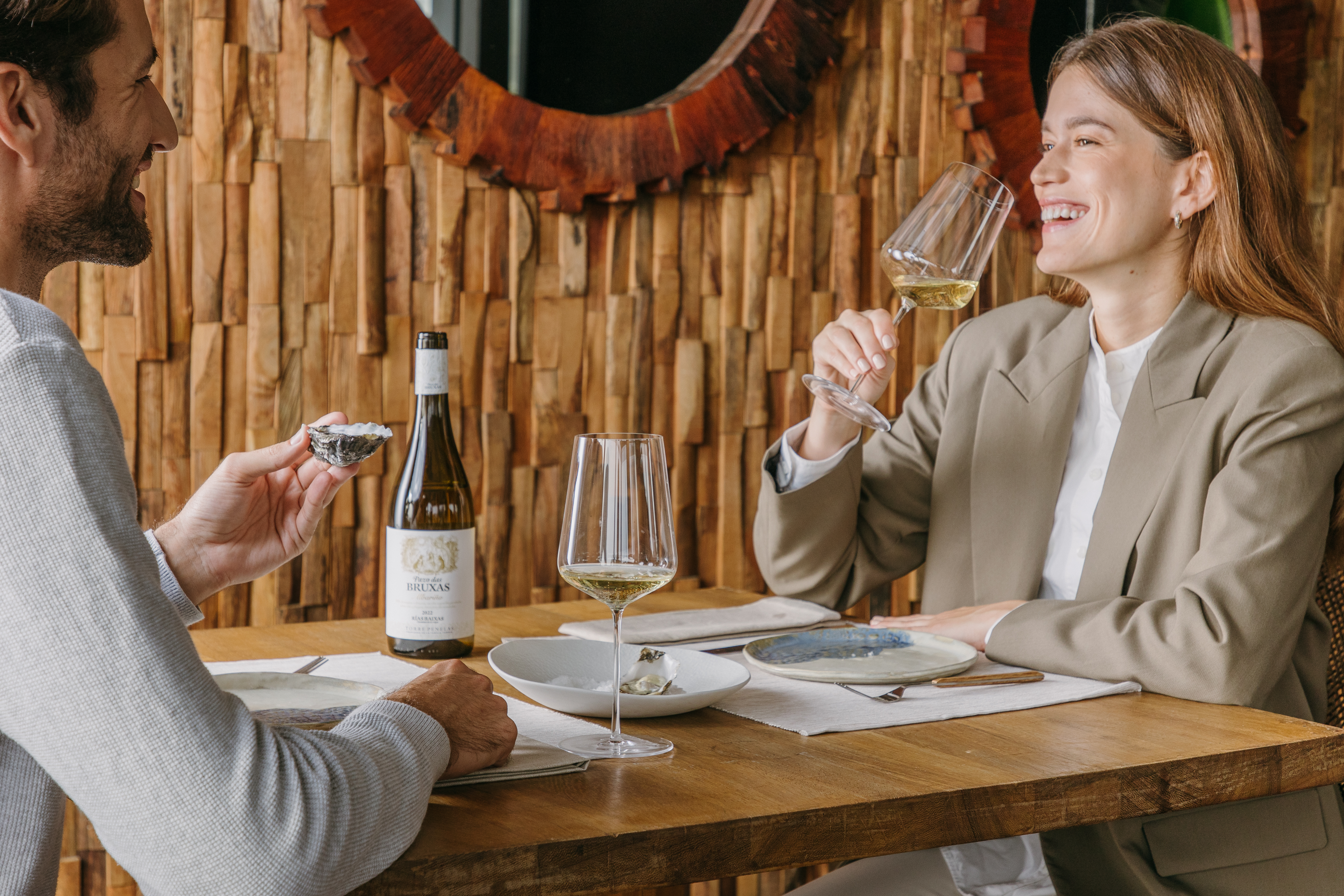 Una pareja disfrutando de una comida maridada con el vino Pazo das Bruxas, propiedad de Familia Torres. 
